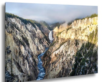 May include: A scenic landscape print featuring a waterfall cascading into a river that winds through a deep canyon. The canyon walls are a mix of tan and brown, with patches of green trees. The sky is overcast with a touch of sunlight.