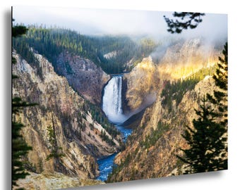 May include: A scenic landscape print featuring a waterfall cascading into a river. The image showcases a canyon with rocky cliffs, lush green trees, and a misty sky. The water is a vibrant blue, and the overall scene is bathed in sunlight.