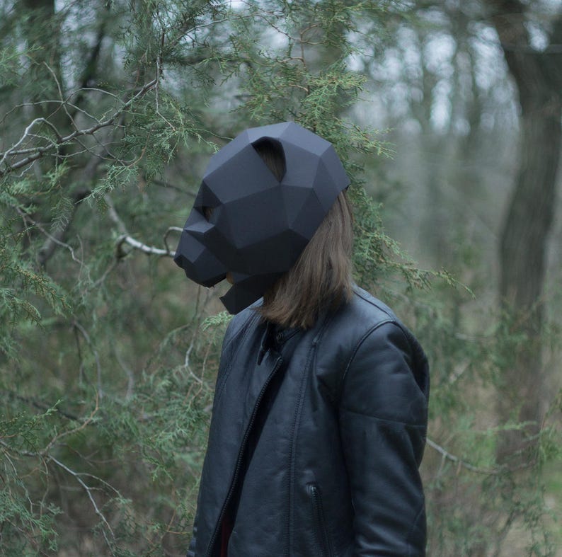 Op de afbeelding: Een persoon draagt ​​een zwart origami-achtig dierenmasker met een zwart leren jack.