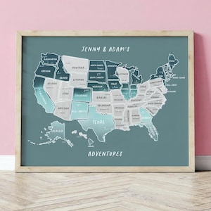May include: A framed map of the United States, teal in colour, with each state labelled. The state outlines are white and teal. The text "JENNY & ADAM'S ADVENTURES" is written on the map.