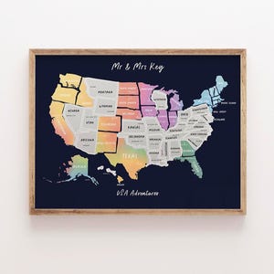 May include: A framed map of the United States with each state colored in a different hue. The map is labeled "Mr & Mrs Key" and "USA Adventurers" in white script. The frame is a light brown color.