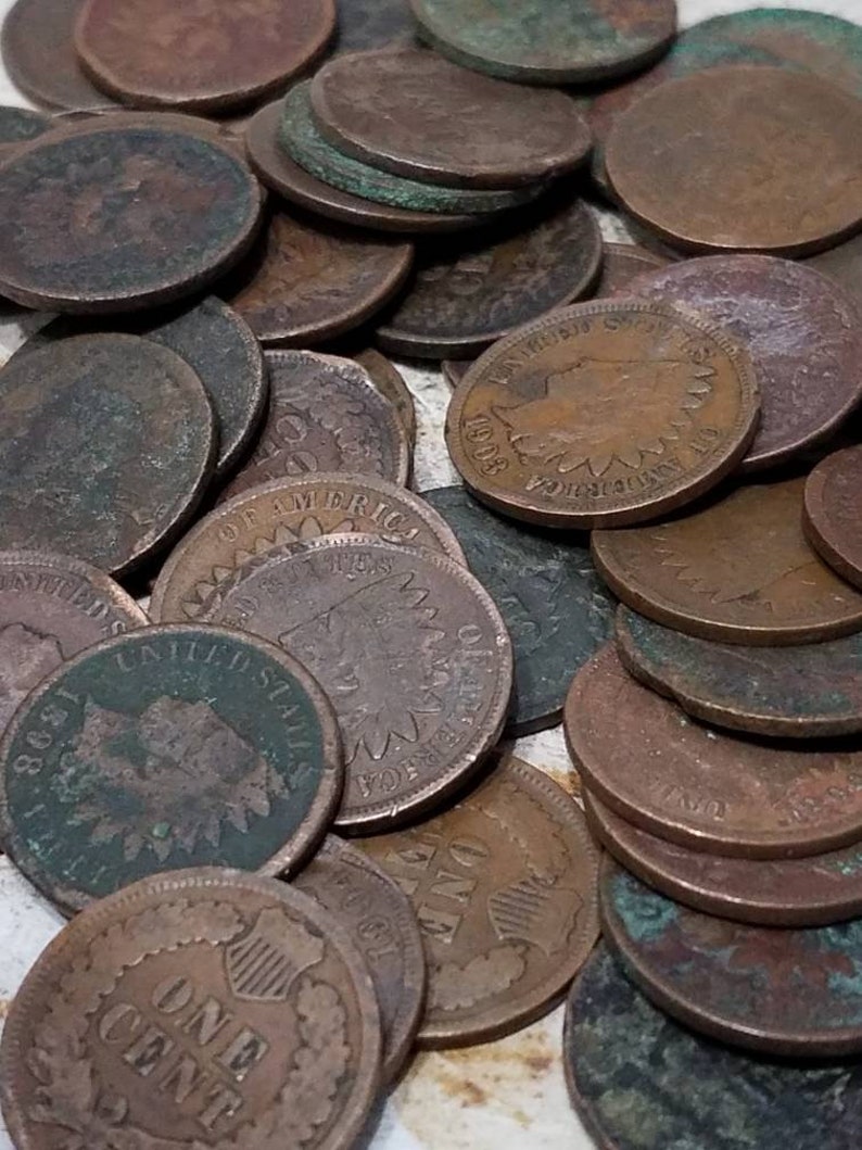 Pu&ograve; includere: Una collezione di antiche monete da un centesimo di dollaro USA, con varie date e disegni. Le monete mostrano segni di et&agrave;, con una miscela di patina marrone e verde. Alcune monete mostrano il testo "ONE CENT" e "UNITED STATES OF AMERICA".