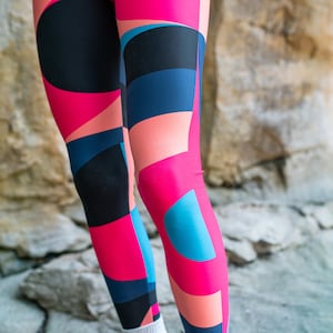 Op de afbeelding: Een legging met een geometrisch patroon in tinten roze, blauw en zwart.