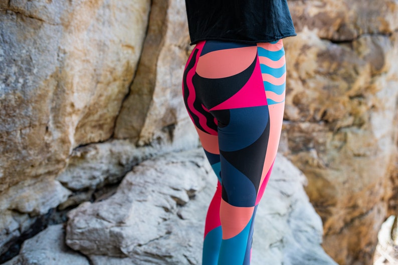 Op de afbeelding: Een legging met een geometrisch patroon in tinten roze, blauw en zwart. De legging is gemaakt van een rekbare, comfortabele stof en perfect voor het sporten of boodschappen doen.