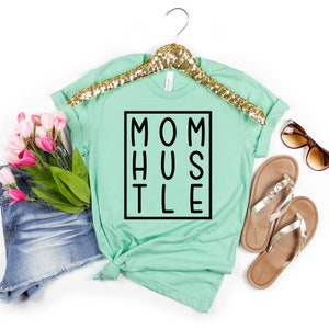 May include: A light green t-shirt with the text "MOM HUSTLE" in a black box.