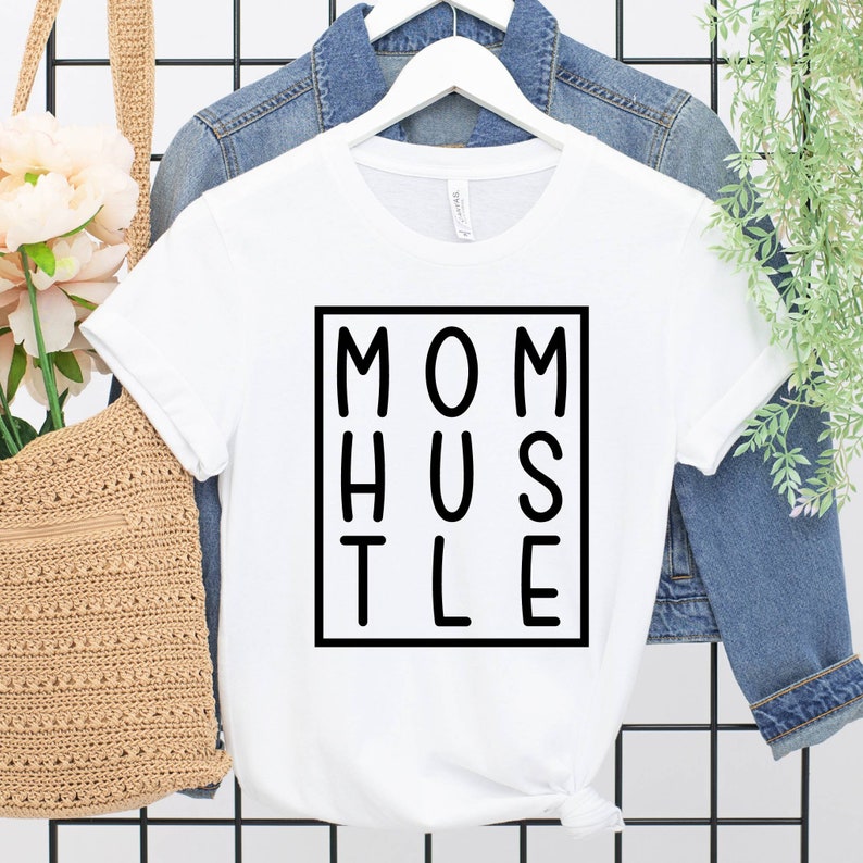 May include: White t-shirt with black text that reads "MOM HUSTLE" inside a black square.
