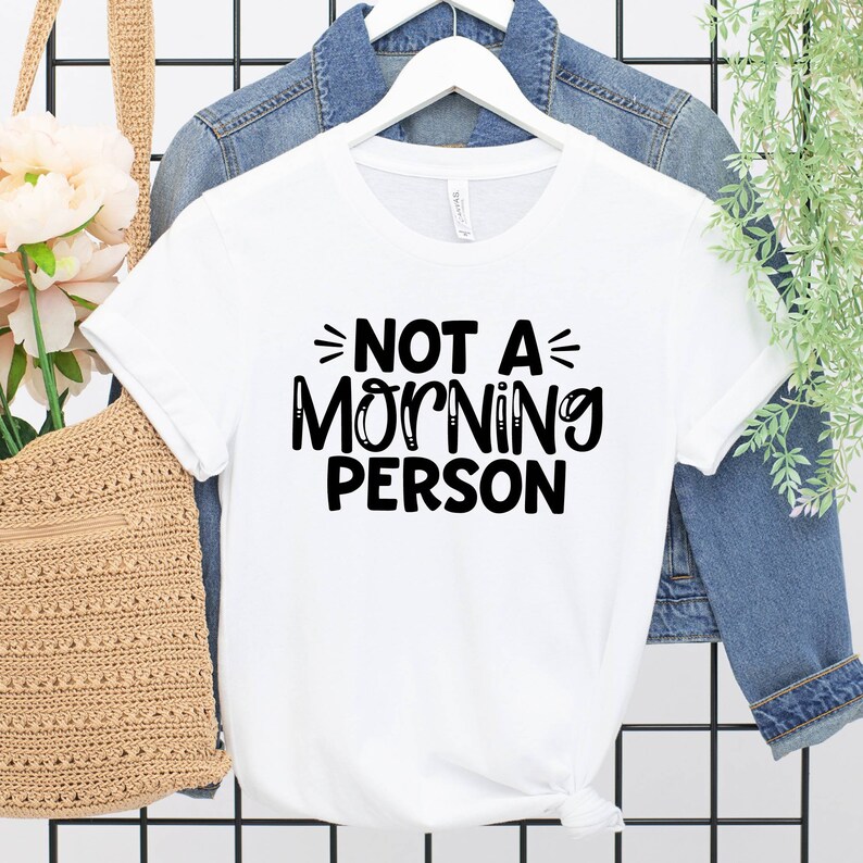 Pu&ograve; includere: Maglietta bianca con testo nero che dice "Not a Morning Person".