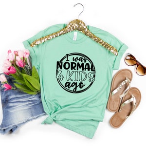 May include: A light green t-shirt with a black circle graphic that says "I was normal 4 kids ago".