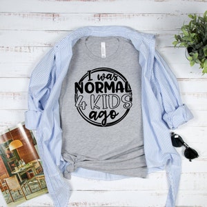 May include: A gray t-shirt with a black circle graphic that says "I was normal 4 kids ago".