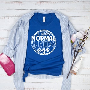 May include: A royal blue t-shirt with white text that reads "I was normal 4 kids ago" in a circle.