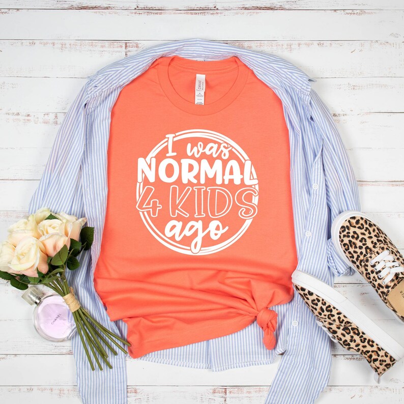 May include: A coral orange t-shirt with white text that reads "I was normal 4 kids ago" in a circle.