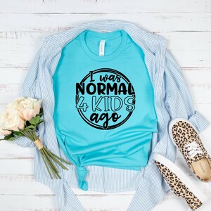 May include: A turquoise blue t-shirt with a black circle graphic that says "I was normal 4 kids ago".