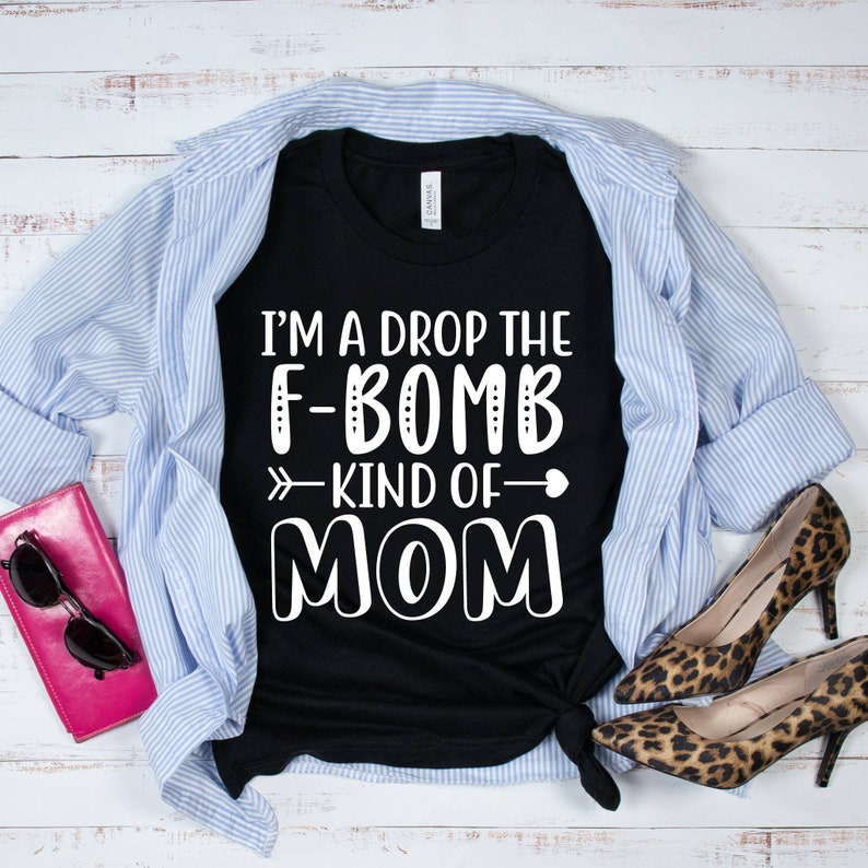 May include: Black t-shirt with white text that reads "I'm a drop the F-bomb kind of mom" with a heart and arrow graphic.