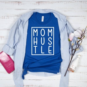 May include: A royal blue t-shirt with a white graphic that says "MOM HUSTLE" in a box.