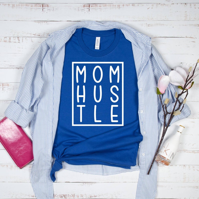 May include: A royal blue t-shirt with a white graphic that says "MOM HUSTLE" in a box.