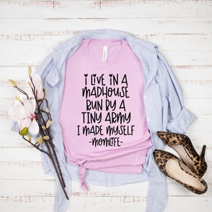 May include: Pink t-shirt with black text that reads "I live in a madhouse run by a tiny army I made myself -momlife-"