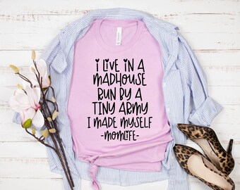 May include: Pink t-shirt with black text that reads "I live in a madhouse run by a tiny army I made myself -momlife-"