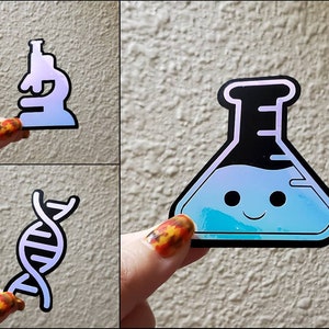 May include: Three iridescent stickers with science themes: a microscope, a beaker with a smiley face, and a double helix DNA strand.