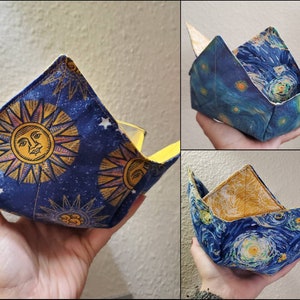 May include: Three fabric bowl cozies. One features a blue background with yellow stars and a yellow sun with a face. The other two feature a blue background with a swirling white and yellow pattern.