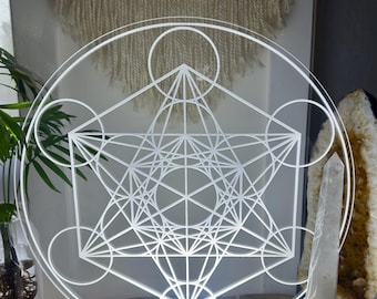 May include: A white acrylic geometric light sculpture with a wooden base. The sculpture features a circular design with a complex geometric pattern inside. The light is on and illuminating the pattern.