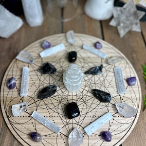 May include: A wooden crystal grid featuring a geometric pattern, encircled by an assortment of crystals and stones. The crystals include clear quartz, amethyst, black obsidian, and selenite. The arrangement is on a wooden surface, creating a spiritual and decorative display.