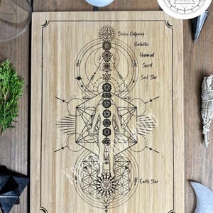 May include: A bamboo board with an engraved geometric design featuring a human figure, chakras, and celestial symbols. The text includes "Divine Gateway," "Galactic," and "Earth Star." The board has a decorative border and the word "BAMBOO" at the bottom.