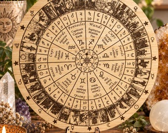 May include: A circular wooden board featuring laser-engraved astrological and tarot imagery. The design includes zodiac signs, planetary symbols, and tarot card illustrations arranged in a radial pattern, with the text Krystal & Wood at the top.
