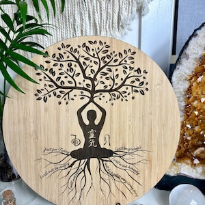 May include: A round wooden plaque featuring a tree of life design. The tree has a person meditating at its centre, with roots that have affirmations written on them. The affirmations are: Just for Today, I will not be angry, I will not worry, I will be grateful, I will work honestly, and I will be kind to every living thing.