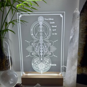 May include: A white acrylic light-up sign with a geometric design and the words "Divine Gateway", "Galactic", "Universal Spirit", "Soul Star", and "Earth Star".