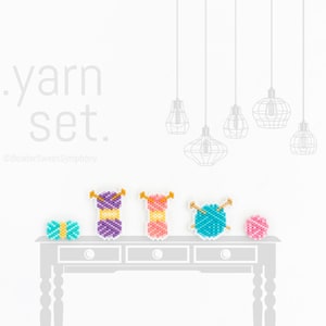 Peut inclure: Un ensemble de cinq breloques en forme de pelote de laine colorées, comprenant du violet, du rose, du bleu et du jaune. Les breloques sont disposées sur une table blanche avec un fond blanc. Le texte "yarn set." est écrit en noir en haut de l'image.