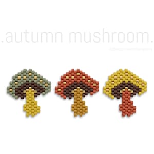 May include: Three beaded mushroom charms in autumnal colors. The mushrooms are green, red, and yellow with brown stems and gold accents.