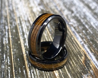May include: Two black tungsten carbide rings with a brown wood inlay. The rings are stacked on top of each other.
