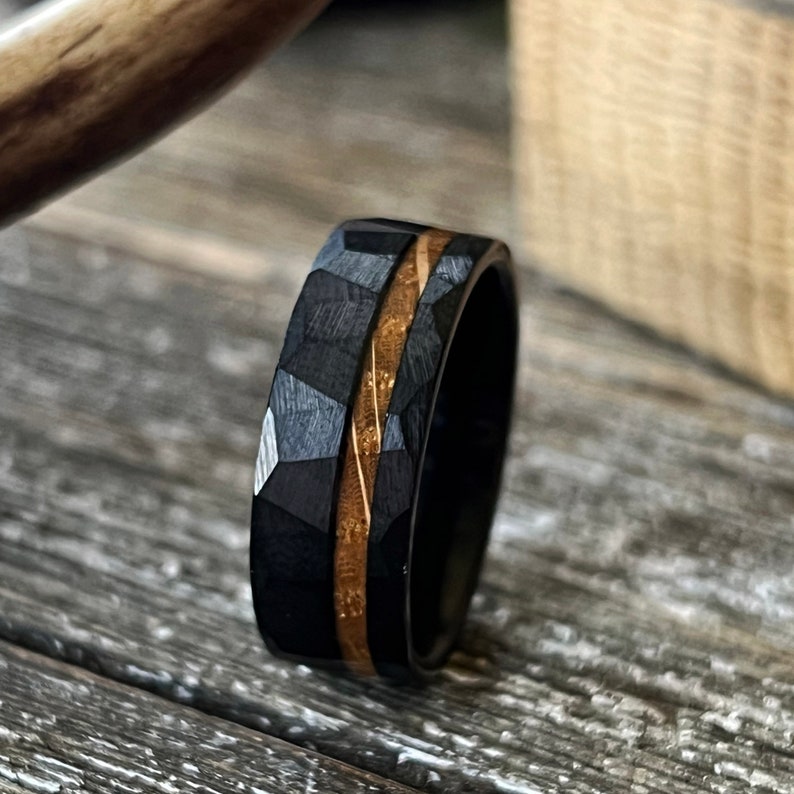 Closeup of black tungsten hammered band with wood whiskey barrel ring inlay