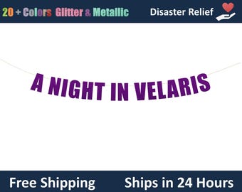 May include: A banner featuring purple capital letters strung together on a thin white cord. The letters spell out the phrase A NIGHT IN VELARIS. The banner is displayed against a plain white background, showcasing the bold, block-style font.
