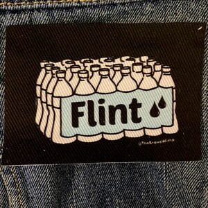 Puede incluir: Una ilustración en blanco y negro de una caja de botellas de agua con la palabra "Flint" y un gráfico de gota de agua en la parte delantera. El texto "@TheBraveWimp" está en la parte inferior de la imagen.