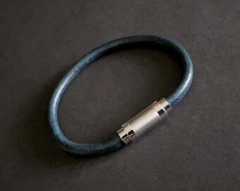May include: A dark blue leather bracelet with a silver magnetic clasp.