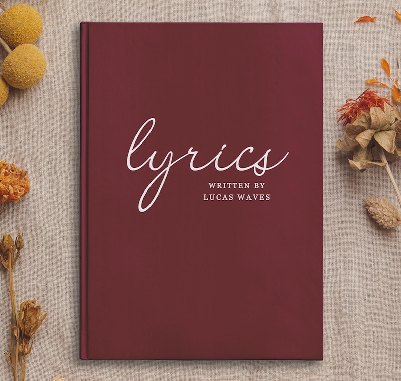 May include: A burgundy hardcover journal with the word "lyrics" written in white cursive script. The text "written by Lucas Waves" is printed in white below the word "lyrics".
