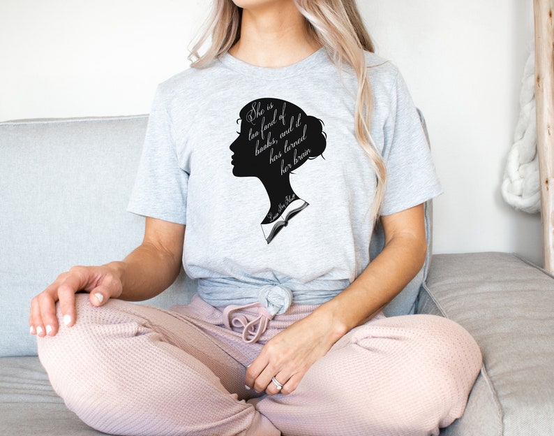 Puede incluir: Una camiseta gris con una silueta negra de la cabeza de una mujer y el texto "She is too fond of books, and has loved her brain" impreso en la parte delantera.