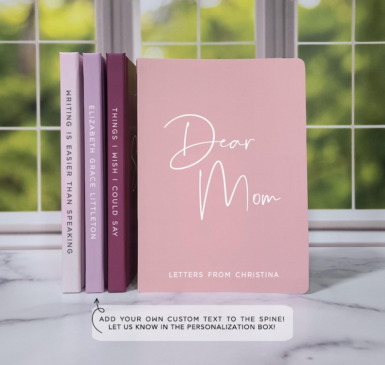 Puede incluir: Un conjunto de cuatro diarios de color rosa y morado con el texto "Dear Mom" en la portada. Los lomos de los diarios est&aacute;n en blanco y se pueden personalizar con texto personalizado. El texto "Letters from Christina" est&aacute; impreso debajo del t&iacute;tulo.