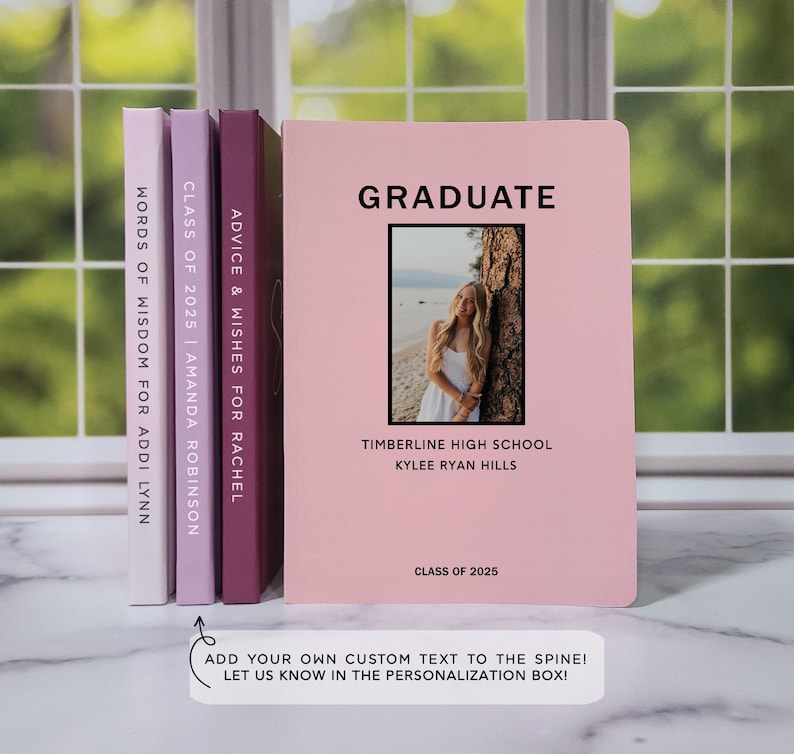 May include: Three pink, purple, and maroon notebooks with the text "ADVICE & WISHES FOR RACHEL", "CLASS OF 2025 | AMANDA ROBINSON", and "WORDS OF WISDOM FOR ADDI LYNN" on the spines. The front cover of the pink notebook has the text "GRADUATE" in black, a photo of a young woman in a white dress, and the text "TIMBERLINE HIGH SCHOOL", "KYLEE RYAN HILLS", and "CLASS OF 2025".