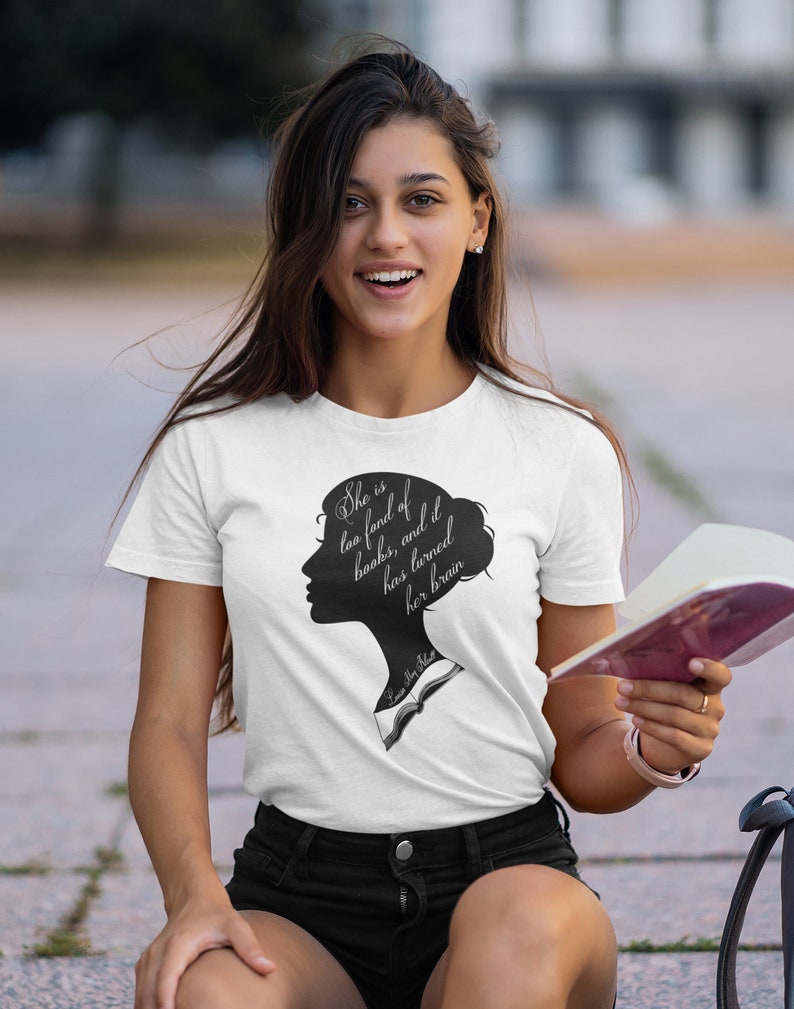 Puede incluir: Una camiseta blanca con una silueta negra de la cabeza y los hombros de una mujer. El texto "She is too fond of books, and it has turned her brain" est&aacute; impreso en la camiseta.