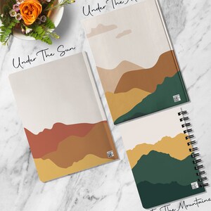 Puede incluir: Tres cuadernos diferentes con paisajes de monta&ntilde;as abstractas. El primer cuaderno se titula "Bajo el sol" y presenta una cordillera amarilla, naranja y marr&oacute;n. El segundo cuaderno se titula "Bajo la luna" y presenta una cordillera beige, marr&oacute;n y verde. El tercer cuaderno se titula "En las monta&ntilde;as" y presenta una cordillera amarilla, verde y blanca.