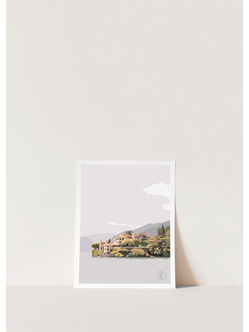 Op de afbeelding: Een ingelijste kunstdruk met een kustlandschap met gebouwen en bergen. Het kunstwerk gebruikt gedempte tinten grijs, beige en groen. De print wordt weergegeven tegen een witte achtergrond.