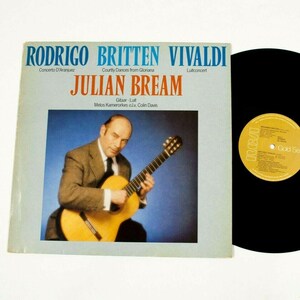 Puede incluir: Un álbum de vinilo vintage con Julian Bream tocando la guitarra clásica. La portada del álbum tiene texto en azul y naranja, con los nombres Rodrigo, Britten y Vivaldi. El disco es negro con una etiqueta dorada.