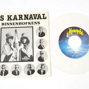 May include: A vintage vinyl record and album cover. The album cover features the text "'T IS KARNAVAL DE BINNENHOFKENS" with a black and white photo of three people in costume. The record is white with a blue and yellow label.