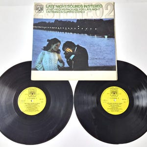 Op de afbeelding: Een vintage vinylalbum getiteld "Late Night Sounds in Stereo". De albumhoes toont een stel bij een water in de nacht. Twee zwarte vinylplaten zijn zichtbaar, elk met een geel label.