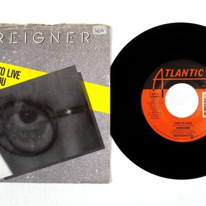 Könnte beinhalten: Eine Vinyl-Schallplatte und ihr Albumcover. Das Albumcover ist grau mit dem Bandnamen "FOREIGNER" und dem Songtitel "I DON'T WANT TO LIVE WITHOUT YOU" in Gelb. Die Schallplatte ist schwarz mit einem orangefarbenen und weißen Label.