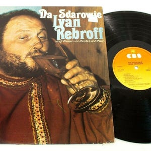 Può includere: Copertina di un album in vinile vintage con un uomo che beve da un bicchiere, con il titolo "Da Sdarowie Ivan Rebroff" e testo in tedesco. Un disco in vinile nero è accanto alla copertina dell'album. La copertina dell'album è marrone e rossa.