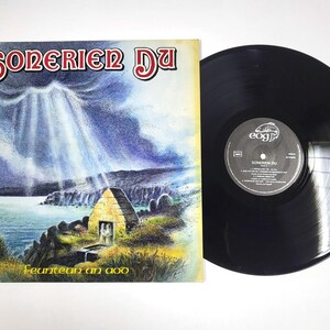 Op de afbeelding: Een vintage vinylplaat en albumhoes. De albumhoes toont de tekst "SONERIER DU" in rood en wit, met een illustratie van een stenen structuur en een kustlandschap. De vinylplaat is zwart.