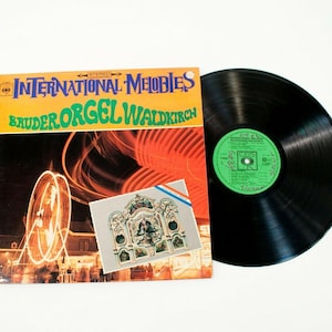 May include: A vintage vinyl record album titled "International Melodies Bruder Orgel Waldkirch" with a colorful cover featuring a Ferris wheel and a small image of an organ. The record is black with a green label.